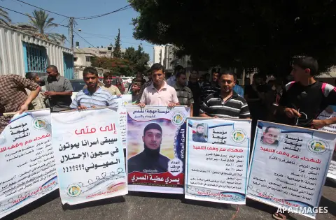 Palestinians hold placards during a protest in solidarity with Palestinian prisoners in Israeli jails, in front of high commissioner for human rights headquarters, in Gaza City on July 22, 2015. Photo by Ashraf Amra