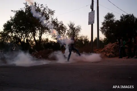 A Palestinian protester throws back a tear gas canister fired by Israeli soldiers during clashes following a protest against the construction of settlements and the confiscation of the Palestinian land, in the West Bank...