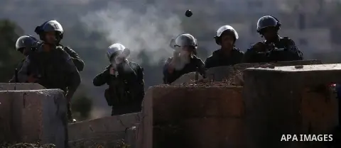 An Israeli soldier fires tear gas towards Palestinian protesters during clashes following a protest against the construction of settlements and the confiscation of the Palestinian land, in the West Bank village of Silwad...