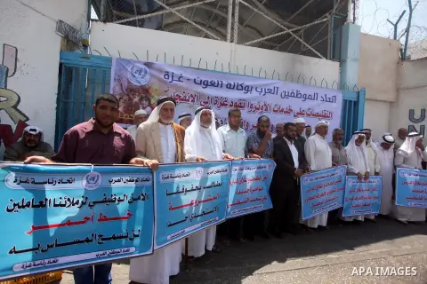 Palestinians hold banners during a protest against the UNRWA decision to reduce of the aid in front of the headquarters United Nations Relief and Works Agency (UNRWA), in Gaza city on July, 26, 2015. Photo by Ashraf Amra