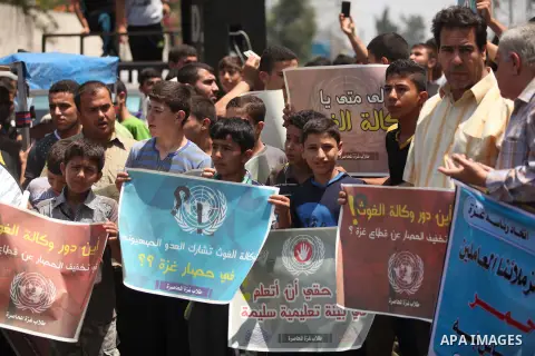 Palestinians hold banners during a protest against the UNRWA decision to reduce of the aid in front of the headquarters United Nations Relief and Works Agency (UNRWA), in Gaza city on July, 26, 2015. Photo by Ashraf Amra