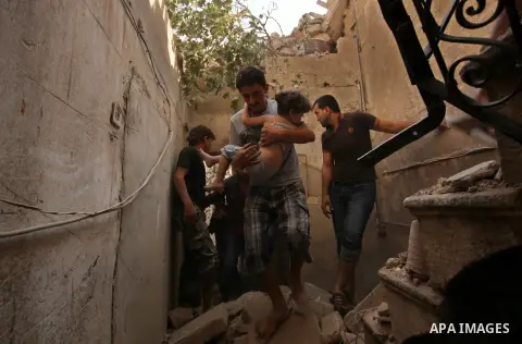 A Syrian man carries a girl on the rubble of a house after a reported missile fired by Syrian government forces hit a residential area in the Jeb Al-Qubbah district in the northern Syrian city of Aleppo on July 27, 2015....
