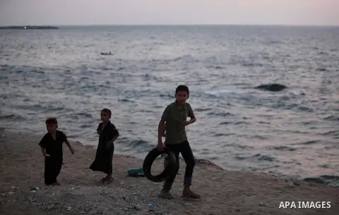 Palestinian children walk along the beach of Gaza city during the sunset, on July 27, 2015. Independent Commission for Human Rights warned Saturday of the aggravated humanitarian situation in Gaza due to continued electr...