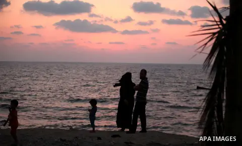 Palestiniansl stand along the beach of Gaza city during the sunset, on July 27, 2015. Independent Commission for Human Rights warned Saturday of the aggravated humanitarian situation in Gaza due to continued electricity...