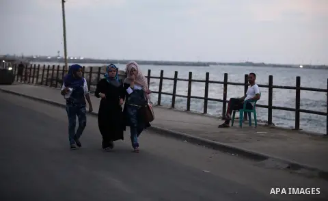 Palestinian girls walk along the beach of Gaza city during the sunset, on July 27, 2015. Independent Commission for Human Rights warned Saturday of the aggravated humanitarian situation in Gaza due to continued electrici...