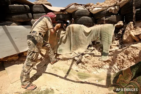 A fighter from the Free Syrian Army takes position following clashes with the pro-regime forces, in Aziza village in the northern Syrian city of Aleppo, on July 28, 2015. Photo by Ameer al-Halbi