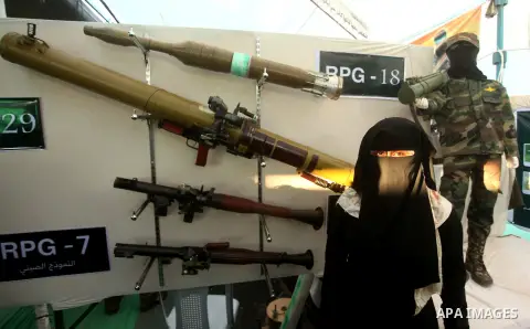 A Palestinian woman watches weapons that used during the Israeli 50-day war on Gaza Strip last summer, during a weapons exhibition in a military-style camp organized by the Hamas movement in Gaza City on July 28, 2015. H...