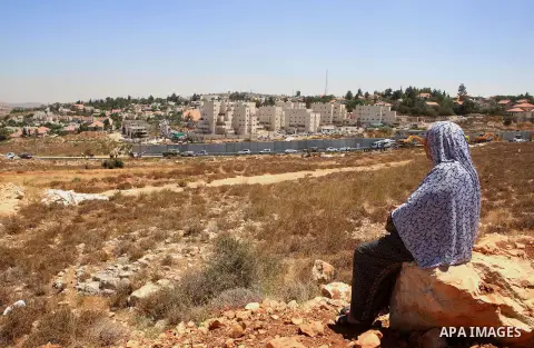 A Palestinian woman, watches Israeli heavy machinery as they demolish vacant apartment blocs by order of Israel's high court, in the West Bank Jewish settlement of Beit El near Ramallah July 29, 2015. Israel gave final a...