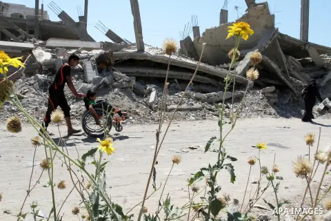 A Palestinian boy pushes the wheelchair of his brother, Ayman Mahmoum, who was injured during the 50-day war between Israel and Hamas militants in the summer of 2014, in Rafah in the southern Gaza Strip on July 29, 2015....