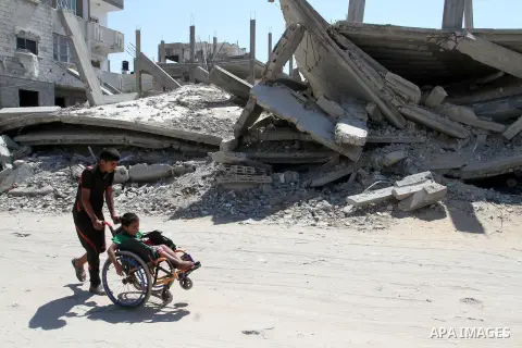 A Palestinian boy pushes the wheelchair of his brother, Ayman Mahmoum, who was injured during the 50-day war between Israel and Hamas militants in the summer of 2014, in Rafah in the southern Gaza Strip on July 29, 2015....