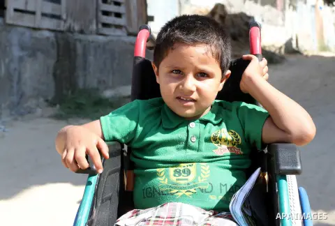 Palestinian boy Ayman Mahmoum, who was injured during the 50-day war between Israel and Hamas militants in the summer of 2014, sits on his wheelchair in a street in Rafah in the southern Gaza Strip on July 29, 2015. Ayma...