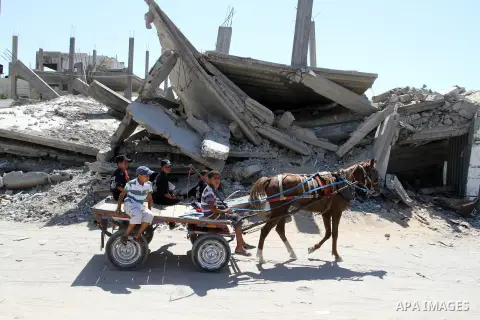 Palestinian children ride a horse cart past the rubble of a house, which was destroyed during the 50-day war between Israel and Hamas militants in the summer of 2014, in Rafah in the southern Gaza Strip on July 29, 2015....