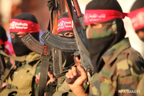 Masked Palestinian militants of the National Resistance Brigades, a group linked to the Democratic Front for the Liberation of Palestine hold their weapons during a military parade against the killing of a 18-month-old P...