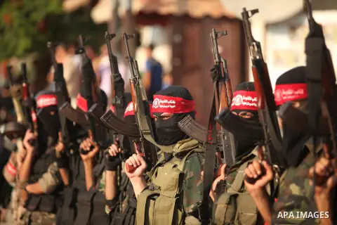 Masked Palestinian militants of the National Resistance Brigades, a group linked to the Democratic Front for the Liberation of Palestine hold their weapons during a military parade against the killing of a 18-month-old P...