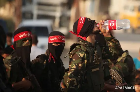 Masked Palestinian militants of the National Resistance Brigades, a group linked to the Democratic Front for the Liberation of Palestine hold their weapons during a military parade against the killing of a 18-month-old P...