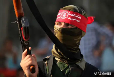 A masked Palestinian militant of the National Resistance Brigades, a group linked to the Democratic Front for the Liberation of Palestine holds his weapon during a military parade against the killing of a 18-month-old Pa...