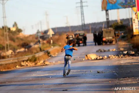 A Palestinian protester uses a slingshot during clashes with Israeli security forces earby the Jalazoun refugee camp and the Jewish settlement of Beit El, north of Ramallah, after a demonstration in reaction to the death...