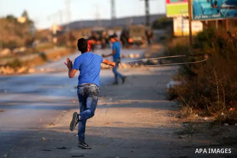 A Palestinian protester uses a slingshot during clashes with Israeli security forces earby the Jalazoun refugee camp and the Jewish settlement of Beit El, north of Ramallah, after a demonstration in reaction to the death...