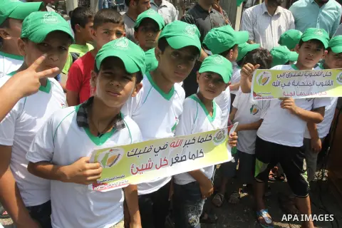 Palestinian children hold banners during the announcement of the start of summer camps organized by the Hamas movement in Gaza city on August 1, 2015. Photo by Mohammed Asad