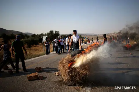 Palestinians burn tires during clashes at the entrance to Duma village near the West Bank city of Nablus, Saturday, Aug. 1, 2015. Tensions remain high after suspected Jewish assailants set fire to a West Bank home and bu...