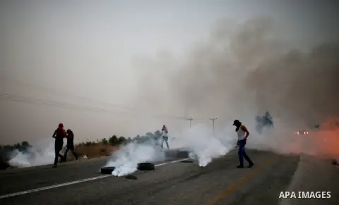 Palestinian protesters run for cover from tear gas fired by Israeli security forces during clashes on a street leading to Duma village, on August 2, 2015, following a demonstration in reaction to the death of a Palestini...