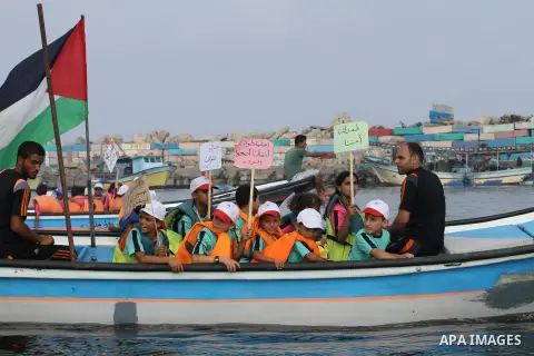 Palestinians riding boats hold Palestinian flags during a protest against the killing of 18-month-old Palestinian Ali Saad Dawabsheh, the toddler who was burned to death by suspected Jewish extremists, at the Seaport of...