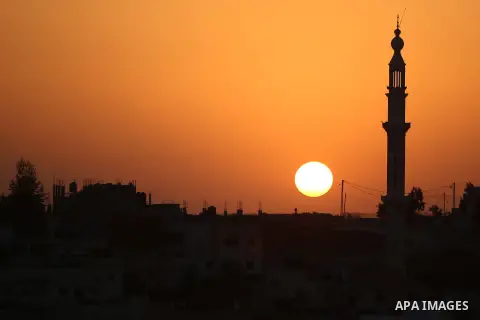 The sun sets behind the minaret of Hera' mosque, in Jalazoun refugee camp, near the West Bank city of Ramallah, on August 9, 2015. Photo by Shadi Hatem