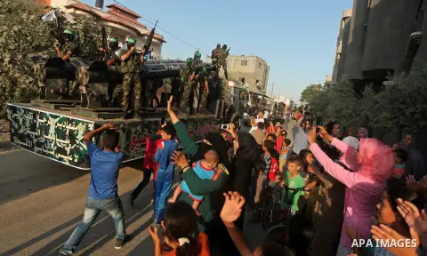 Palestinians look on as members of Ezzedeen al-Qassam brigades, the armed wing of Hamas movement, take part in an anti-Israel parade in Beit Hanoun, in the northern Gaza Strip, on August 11, 2015. Photo by Ashraf Amra