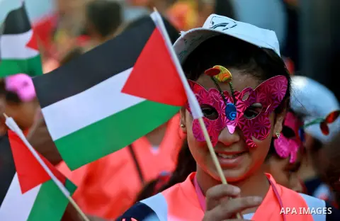 A Palestinian girl holds a flag during a protest against the Israeli blockade on the Gaza Strip and demanding for opening the Rafah crossing, in Gaza city on August 12, 2015. Photo by Yasser Qudih