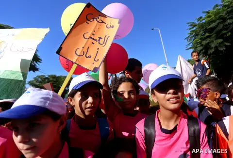 Palestinian children hold banners during a protest against the Israeli blockade on the Gaza Strip and demanding for opening the Rafah crossing, outside the United Nations headquarter in Gaza city on August 12, 2015. Phot...
