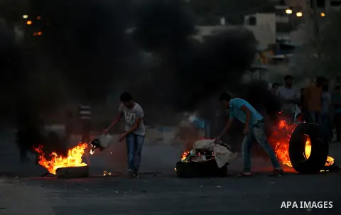 Palestinian protesters burn tires during clashes with Israeli security forces following killed of Rafiq Kamel Al-Taj, in the West Bank village of Beta near Nablus City on August 15, 2015. A police spokesperson said that...