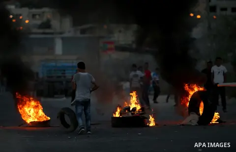Palestinian protesters burn tires during clashes with Israeli security forces following killed of Rafiq Kamel Al-Taj, in the West Bank village of Beta near Nablus City on August 15, 2015. A police spokesperson said that...