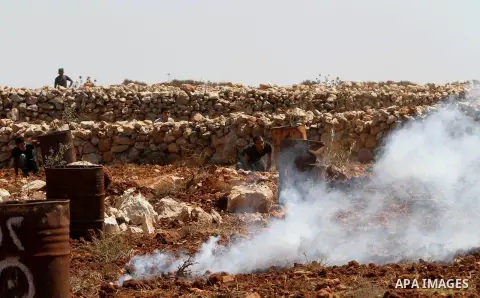 Palestinian protesters take cover from tear gas fired by Israeli security forces during clashes following the attack by settlers at the West Bank village of Qasra near Nablus, 22 August 2015. Ghassan Daghlas, who monitor...