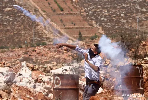 A Palestinian protester throws stones towards Israeli security forces during clashes following the attack by settlers at the West Bank village of Qasra near Nablus, 22 August 2015. Ghassan Daghlas, who monitors settlemen...