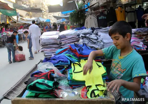 A Syrian boy sells clothes in a market in a rebel-controlled area in the northern Syrian city of Aleppo, on August 31, 2015. Photo by Ameer al-Halbi