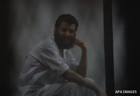 An Egyptian Muslim Brotherhood defendant sits behind the bars during his trial, along with ousted Islamist president Mohamed Morsi (unseen) in Cairo on Sep. 01, 2015. Cairo criminal court resumed proceedings in the 'Qata...
