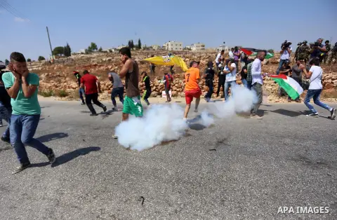 Palestinian protesters run for cover from a tear gas fired by Israeli border policemen during a protest against Jewish settlements in the West Bank village of Nabi Saleh, near Ramallah September 4, 2015. Photo by Shadi H...