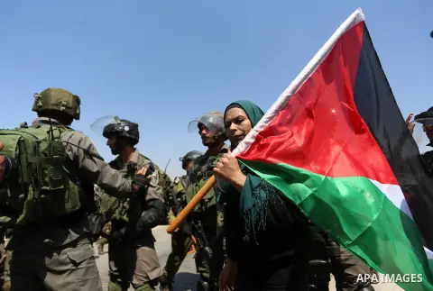 A Palestinian protester waves a Palestinian flag as he stands in front of Israeli border policemen during a protest against Jewish settlements in the West Bank village of Nabi Saleh, near Ramallah September 4, 2015. Phot...