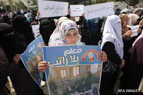 Palestinian teachers hold banners during a protest to demand their salaries and their rights, in Gaza City, on September 7, 2015. Photo by Ashraf Amra