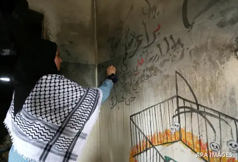 A Palestinian girl paints a graffiti on the wall in Dawabsha family's house in the village of Duma, near the occupied West Bank city of Nablus on September 7, 2015. Riham Dawabsha, the mother of a Palestinian child kille...