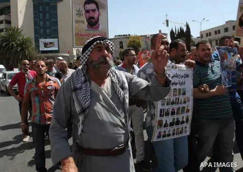 Palestinian protesters hold posters during a protest to show solidarity with Palestinian prisoners in Israeli jails, in the West Bank city of Nablus, on Sep. 17, 2015. Photo by Nedal Eshtayah