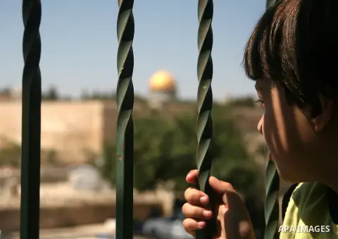 A Palestinian boy looks at the Dome of the Rock mosque as Israeli police blocks the access to Al-Aqsa Mosque, outside the Old City walls in East Jerusalem on September 18, 2015. Israel deployed hundreds of extra police a...