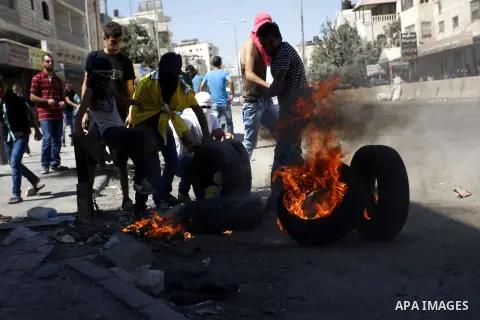 Palestinian protesters burn tires during clashes with Israeli security forces following a demonstration against the Israeli police raid on Jerusalem's al-Aqsa mosque on Tuesday at the Israeli Qalandia checkpoint near the...