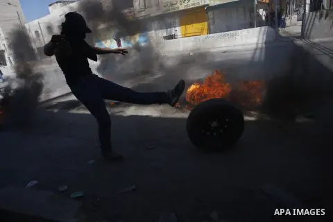 Palestinian protesters burn tires during clashes with Israeli security forces following a demonstration against the Israeli police raid on Jerusalem's al-Aqsa mosque on Tuesday at the Israeli Qalandia checkpoint near the...