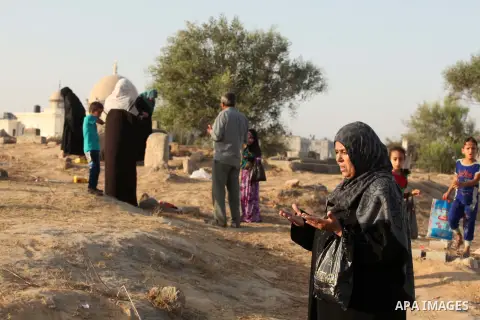 A Palestinian woman prays over the graves of relatives in a cemetery, on the Muslim holiday of Eid al-Adha or or the feast of sacrifice, in Khan Younis in the southern Gaza Strip on September 24, 2015. Muslims across the...