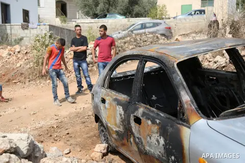 Palestinian boys look at a car belonging to Palestinians, which residents said was burnt by alleged Jewish settlers, in Beit Ilu village, west of Ramallah on October 2, 2015. Two Israeli settlers were shot and killed in...