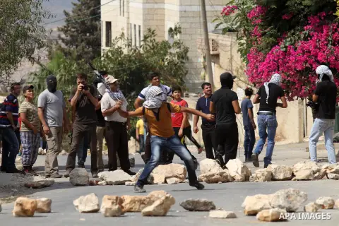 Palestinian protesters throw stones towards Israeli security forces during clashes with Israeli security forces following a protest against the expropriation of Palestinian land by Israel in the West Bank village of Kafr...