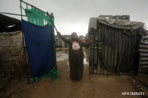 A Palestinian woman, whose house was destroyed by what witnesses said was Israeli shelling during the 50-day war in the summer of 2014, gestures as she stands at her makeshift shelter on a rainy day in Khan Younis in the...