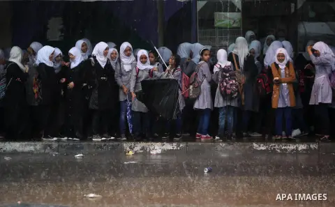Palestinian schoolgirls stand as they go to school on a rainy day in Khan Younis in the southern Gaza Strip October 7, 2015. Photo by Ashraf Amra