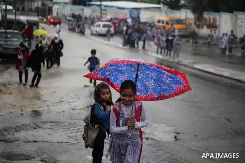 Palestinian students walk in a flooded street during a rainy day in Khan Younis in the southern Gaza Strip October 7, 2015. Photo by Ashraf Amra